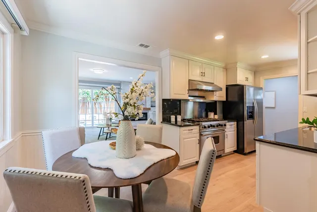 a kitchen with stainless steel appliances granite countertop a stove a refrigerator a kitchen island a table and chairs