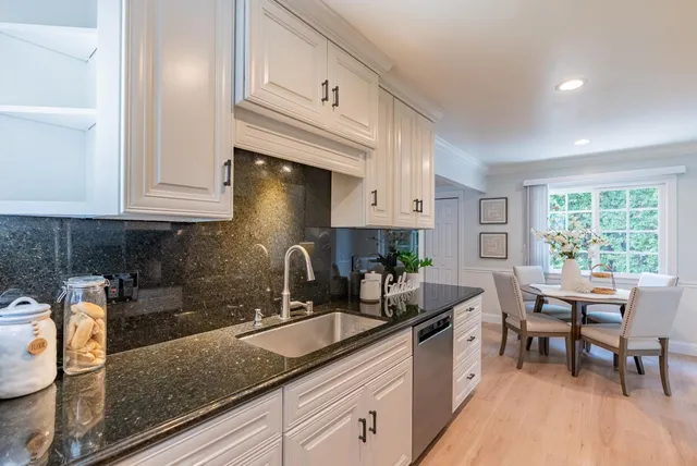 a kitchen with granite countertop a sink a stove and cabinets