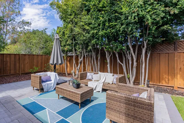 a view of a patio with couches and a table and chairs with wooden floor and fence