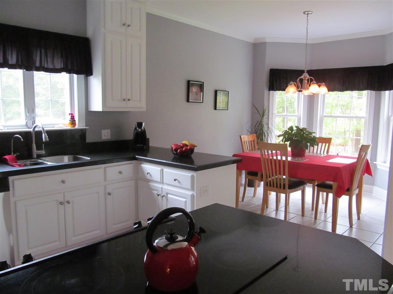3540 Saddle Ridge Road Stem, NC 27581 - Photo 8 of 25 a kitchen with granite countertop a table chairs stove and white cabinets