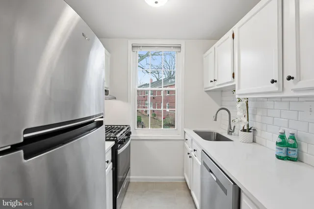 a kitchen with stainless steel appliances a white cabinets sink and a window