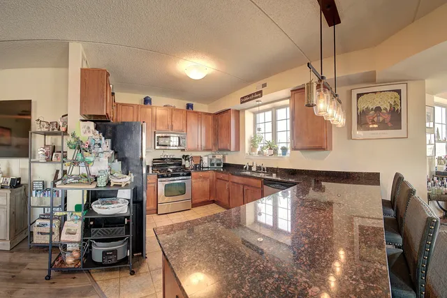 a kitchen with stainless steel appliances granite countertop a refrigerator a stove and a sink with granite countertops