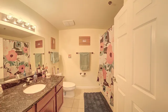 a bathroom with a granite countertop sink toilet a mirror a vanity and shower
