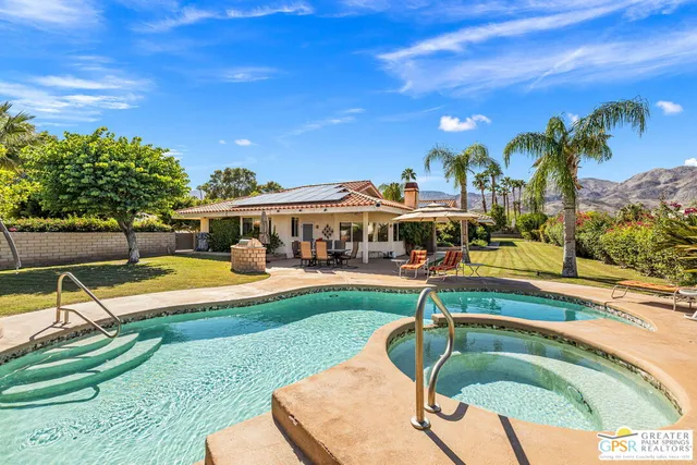 a view of a swimming pool with lawn chairs and plants