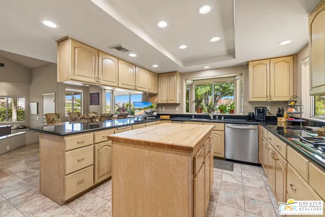 a view of swimming pool with lawn chairs and palm trees