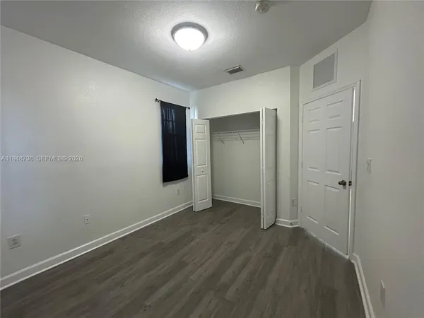 an empty room with wooden floor and closet