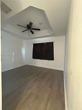 a living room with stainless steel appliances wooden floor and chandelier