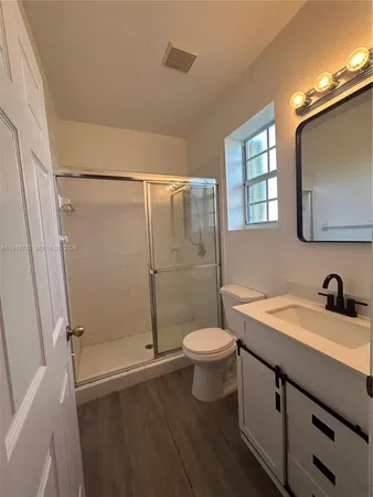 a bathroom with a sink a toilet a mirror and shower