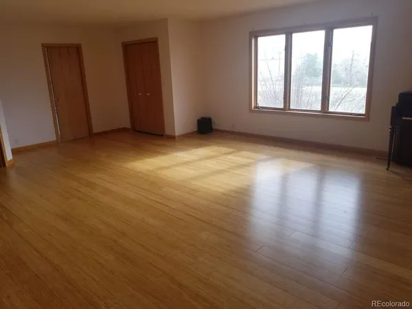 an empty room with wooden floor and windows