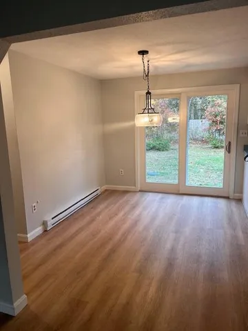 an empty room with wooden floor exposed radiator and windows