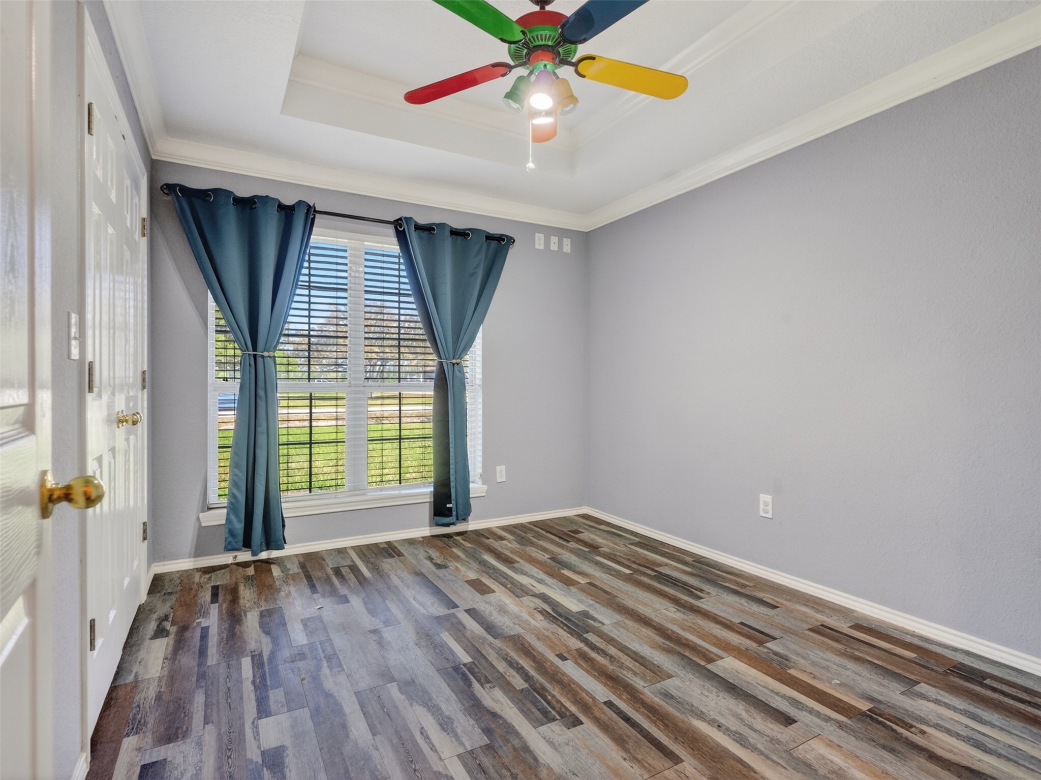 5036 Singletary Road Alvin, TX 77511 - Photo 18 of 35 Bright secondary bedroom featuring tray ceiling detail, large window with natural light, and durable wood-look flooring.