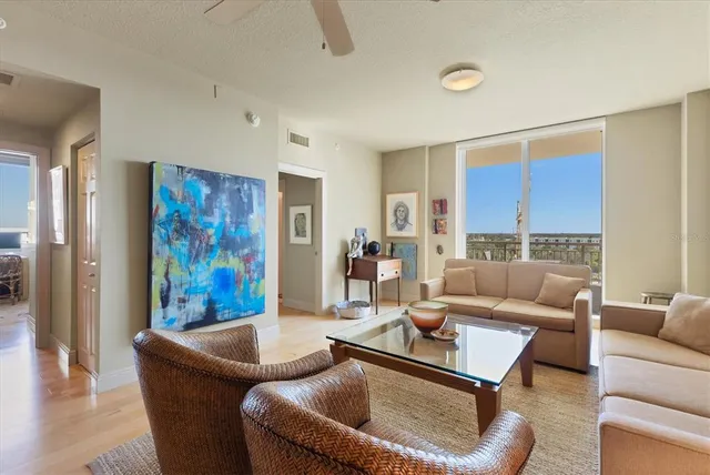 a living room with furniture kitchen view and a wooden floor