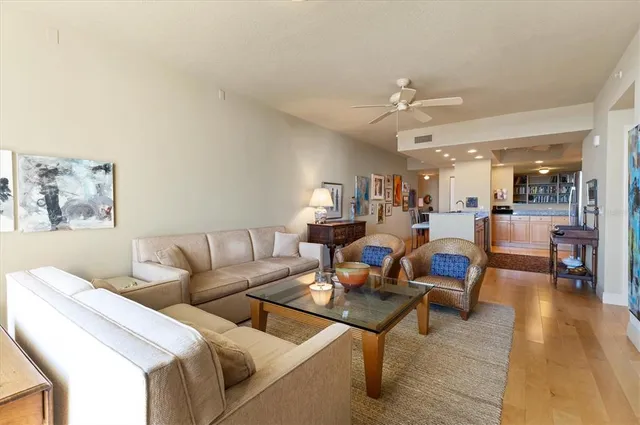 a living room with stainless steel appliances furniture a fireplace a flat screen tv and a kitchen view