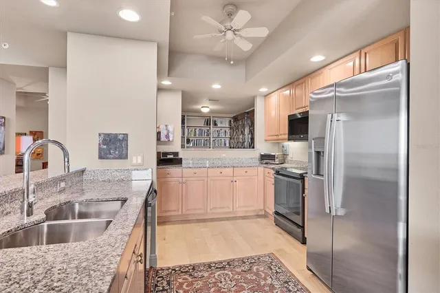 a large white kitchen with stainless steel appliances granite countertop a stove a sink and a refrigerator with wooden floor