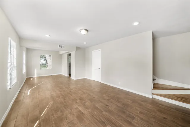 a view of empty room with wooden floor and window