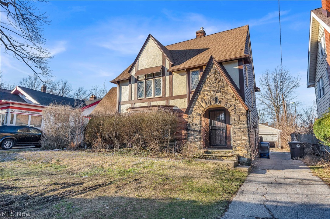 1858 Rudwick Road Cleveland, OH 44112 - Photo 1 of 36 Tudor-style house featuring stone siding, stucco siding, a shingled roof, and a chimney