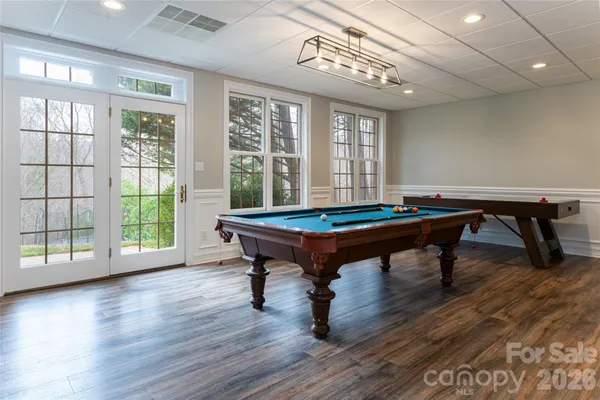 a room with wooden floor pool table and windows