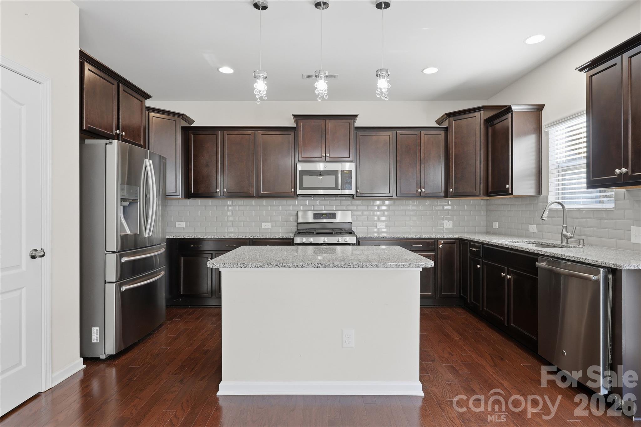 1722 Still River Way Fort Mill, SC 29708 - Photo 13 of 45 a kitchen with stainless steel appliances granite countertop a stove top oven a refrigerator and a granite counter tops with wooden floors