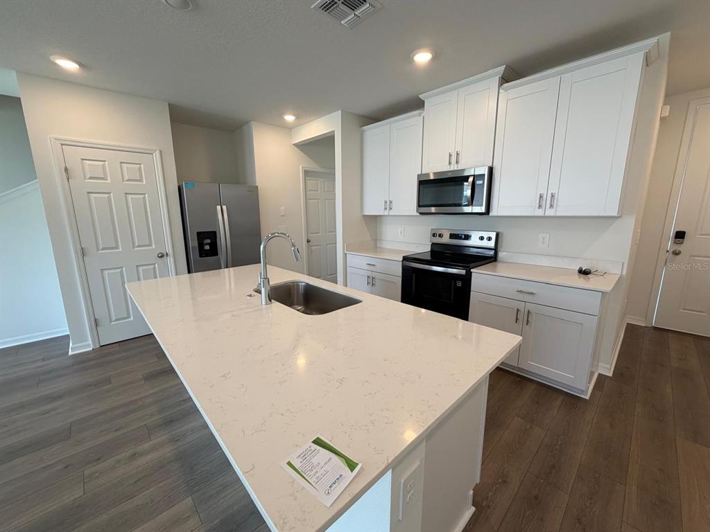 4244 Ranch House Road St. Cloud, FL 34772 - Photo 5 of 34 a kitchen with stainless steel appliances a refrigerator a sink a stove a microwave and wooden floor