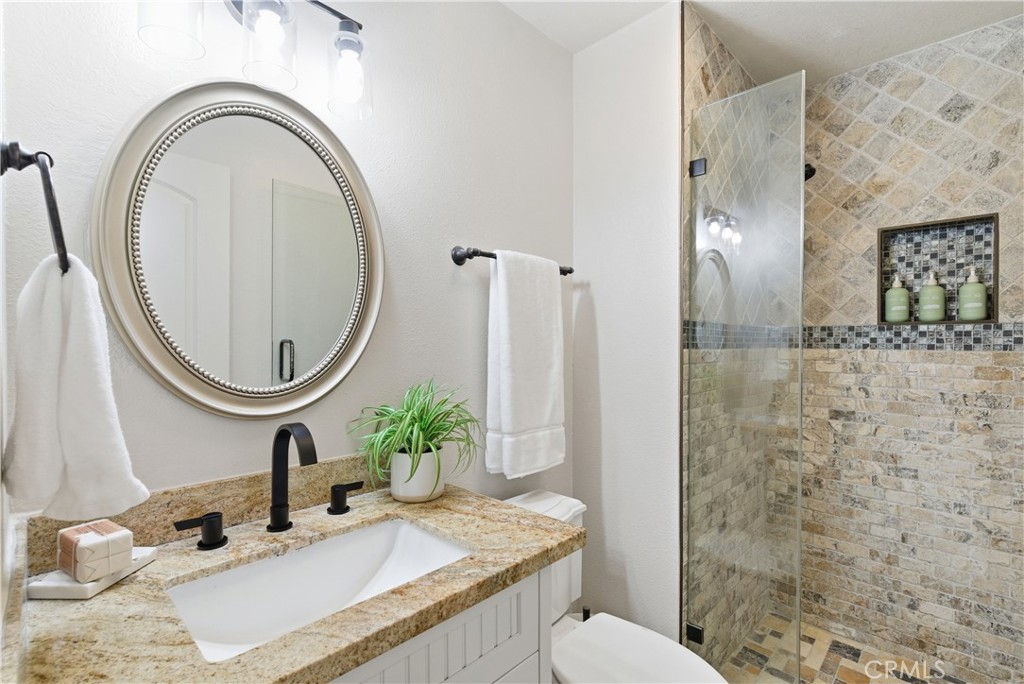 21630 Edward Way Cupertino, CA 95014 - Photo 32 of 59 a bathroom with a granite countertop toilet a sink and a mirror