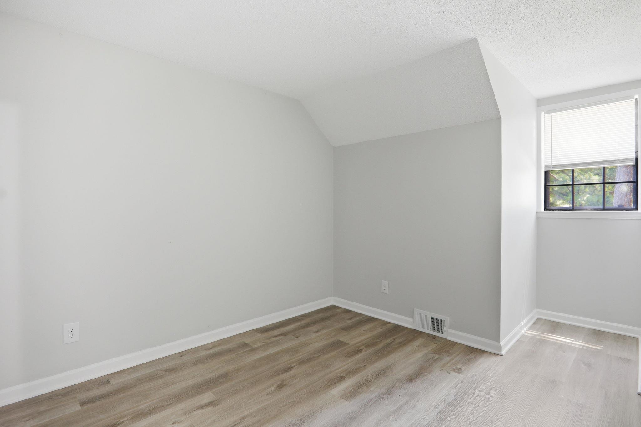 3113 Raleigh Ridge Cove Memphis, TN 38128 - Photo 29 of 38 Room featuring light-toned walls, wood-finish flooring, white baseboards, a window with blinds, and an angled ceiling line