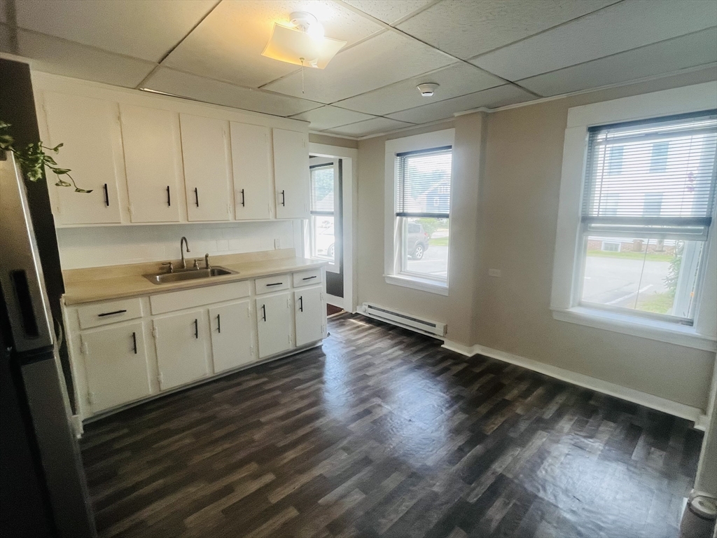 347 Main Street, Unit 2 Douglas, MA 01516 - Photo 2 of 5 a kitchen with wooden floors and white cabinets