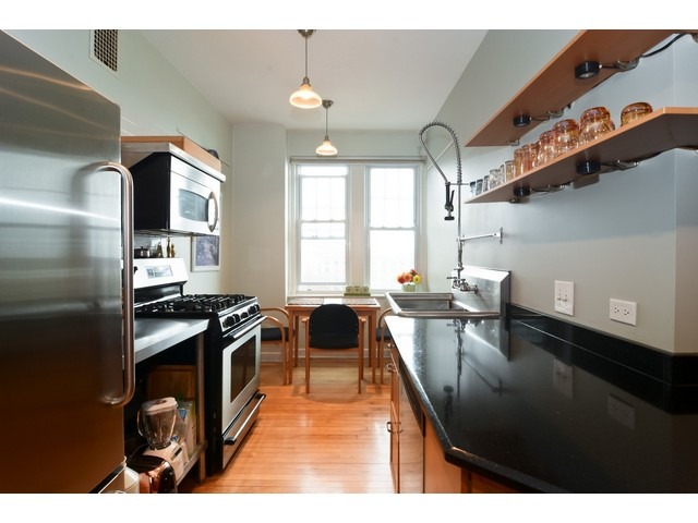 6342 North Sheridan Road, Unit 5B Chicago, IL 60660 - Photo 7 of 25 a kitchen with stainless steel appliances granite countertop a stove a sink dishwasher and cabinets with wooden floor