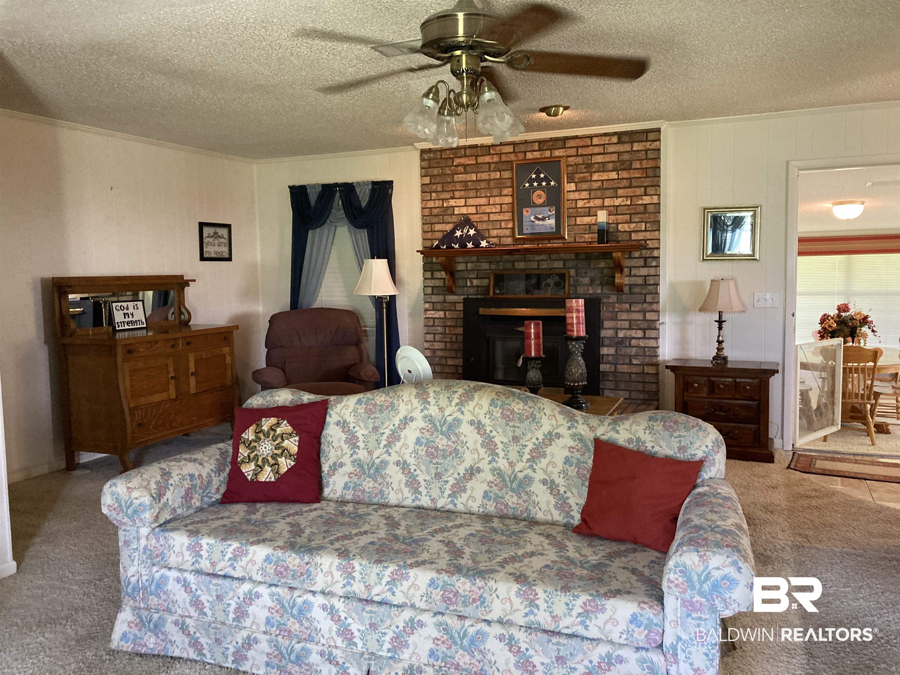 6151 Meadows Road Walnut Hill, FL 32568 - Photo 6 of 29 Carpeted living room featuring ceiling fan, ornamental molding, a textured ceiling, and a brick fireplace