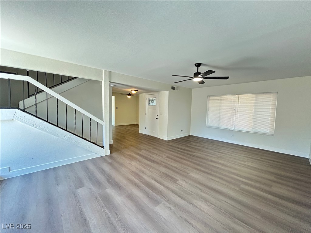 5035 Meadow Grove Court Las Vegas, NV 89120 - Photo 2 of 23 Unfurnished living room with light wood-style floors, ceiling fan, and stairway