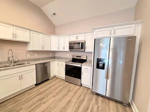 a kitchen with granite countertop a refrigerator stove and sink