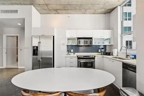 a kitchen with stainless steel appliances a dining table chairs sink refrigerator and stove