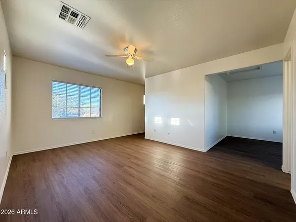an empty room with wooden floor chandelier and windows