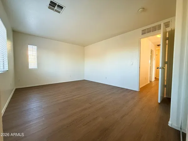 an empty room with wooden floor and windows