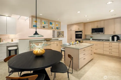 a kitchen with stainless steel appliances a sink a stove a table and chairs