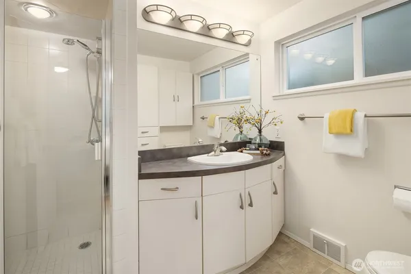 a bathroom with a granite countertop sink a toilet a mirror and shower