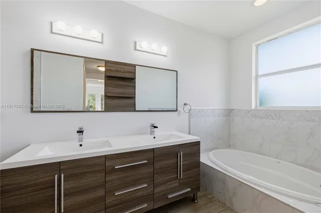a bathroom with a double vanity sink and mirror with bathtub