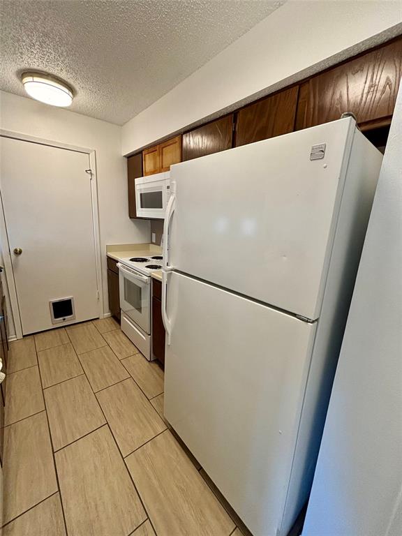 12480 Abrams Road, Unit 2805 Dallas, TX 75243 - Photo 10 of 18 Kitchen with white appliances, a textured ceiling, light countertops, and wood finish cabinetry