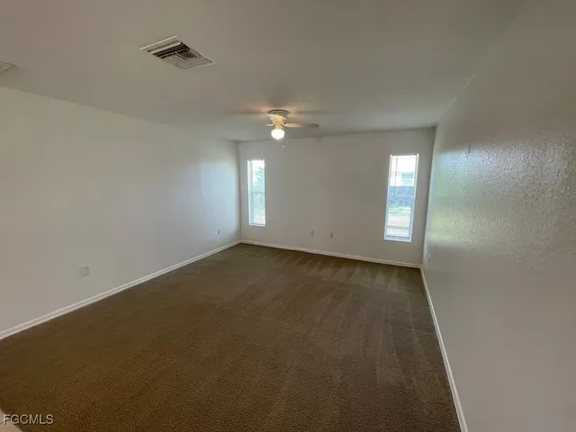 an empty room with windows and fan