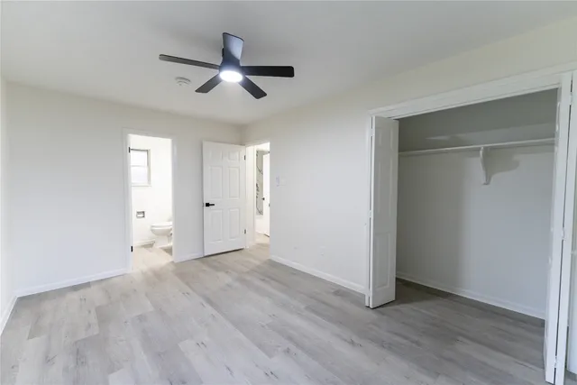 an empty room with wooden floor ceiling fan and windows
