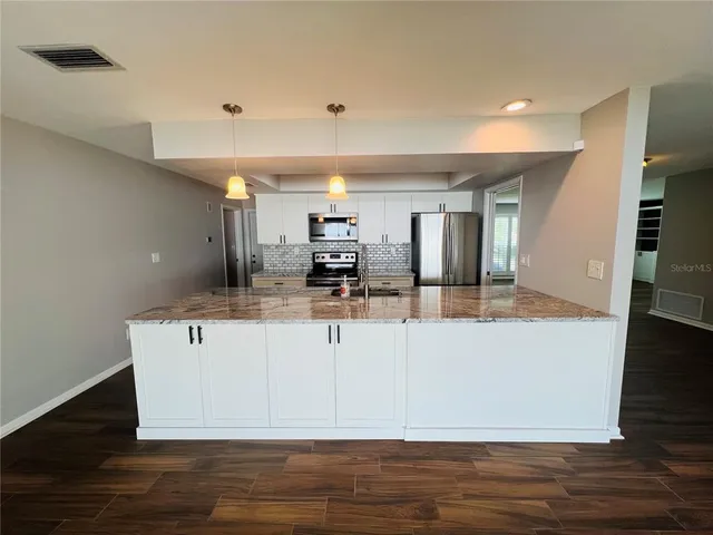 a view of kitchen with stainless steel appliances granite countertop cabinets and wooden floor