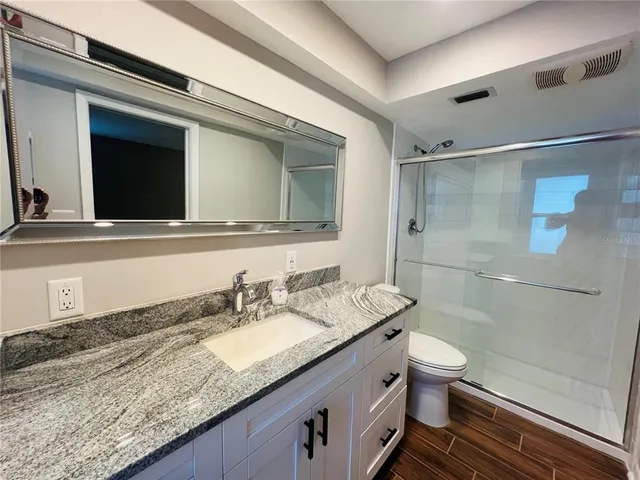 a bathroom with a granite countertop sink a toilet and shower