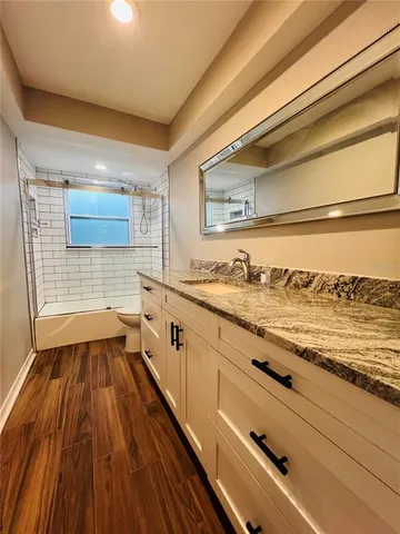 a bathroom with a granite countertop sink and a toilet