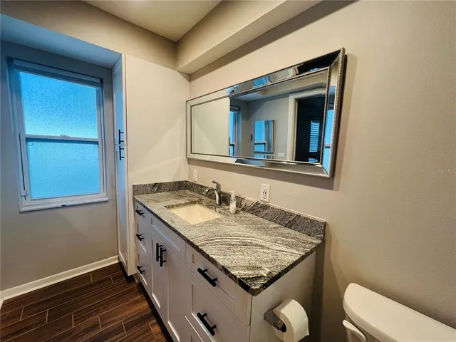 a bathroom with a granite countertop sink and a toilet