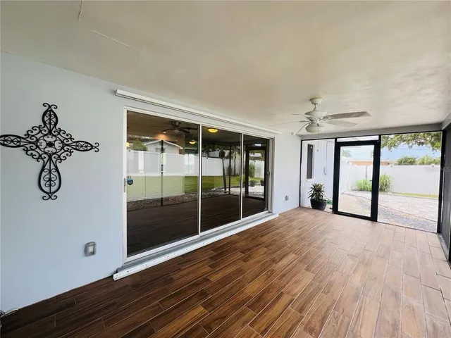 a view of empty room with wooden floor and fan