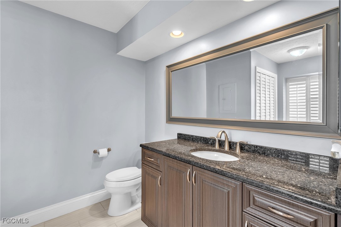 1526 Trafalgar Lane, Unit B Naples, FL 34116 - Photo 11 of 33 a bathroom with a granite countertop sink a toilet and a mirror