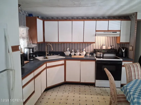 a kitchen with a sink a stove cabinets and a dining table