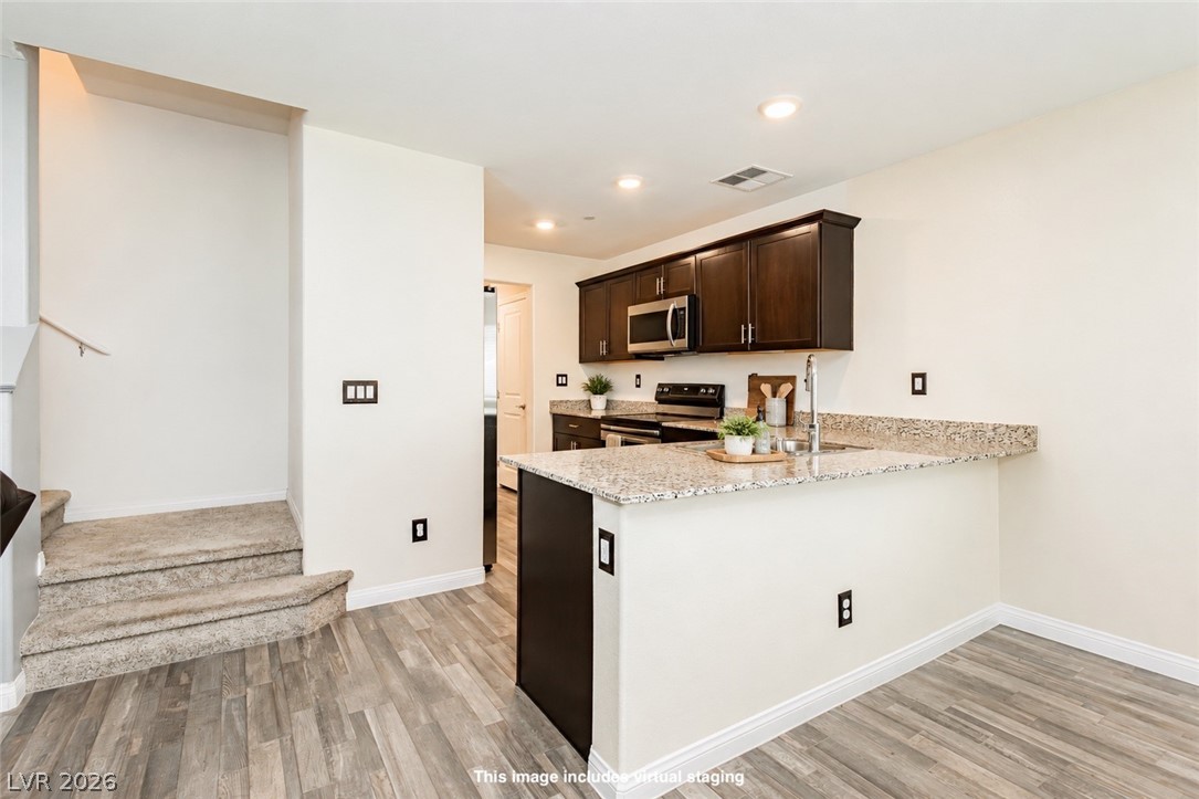 12369 Golden Wreath Road, Unit 2 Las Vegas, NV 89183 - Photo 5 of 19 A contemporary kitchen space boasts dark cabinetry complemented by a light granite island and stainless steel appliances.