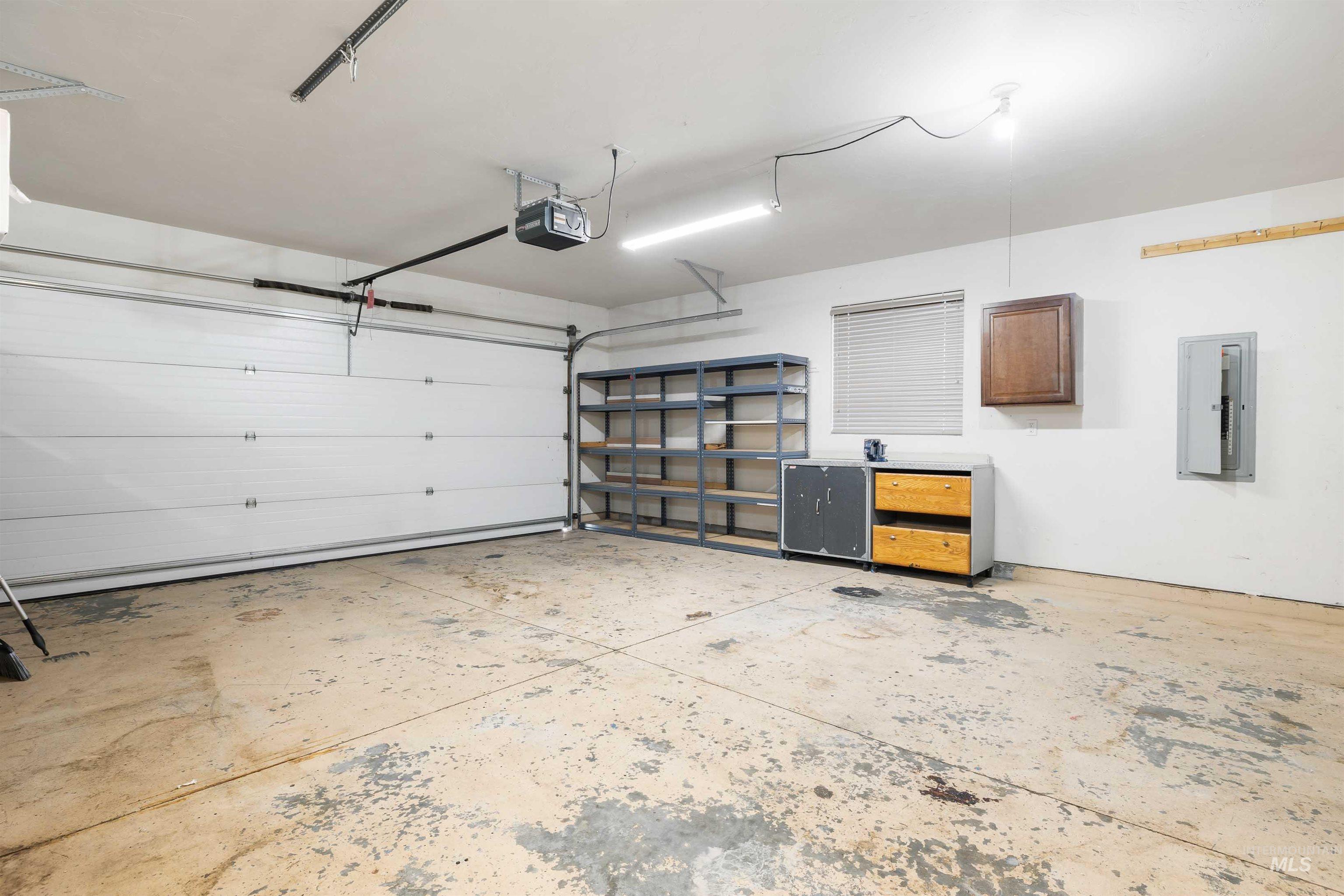 2509 Cedar Ridge Road Twin Falls, ID 83301 - Photo 23 of 36 Attached garage with an overhead door, built-in shelving, and utility cabinetry