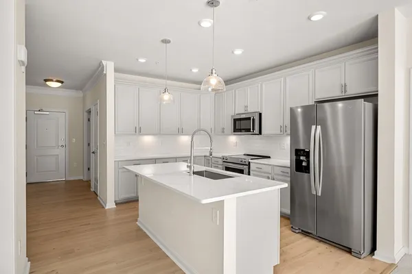 a kitchen with stainless steel appliances granite countertop a refrigerator a stove a sink and white cabinets with wooden floor