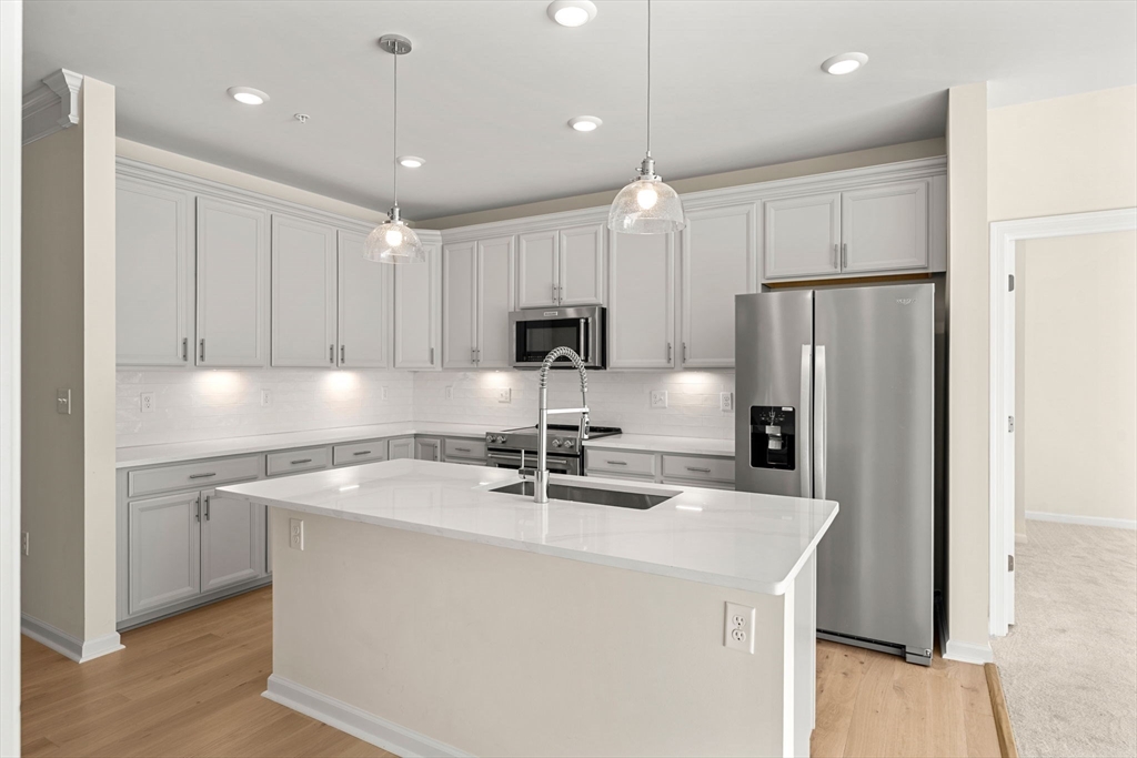2 Stratton Drive, Unit 102 Woburn, MA 01801 - Photo 3 of 32 a kitchen with kitchen island a sink stainless steel appliances and cabinets